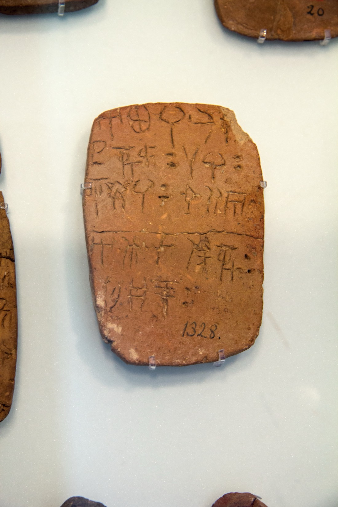 A Linear A clay tablet (HM 1328) from Haghia Triada, incised with rows of signs separated by a ruled line, with a short entry and a number at the foot, an administrative account roughly 3,500 years old.